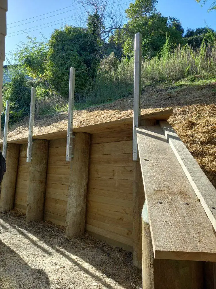Timber retaining wall with galvanised capping brackets